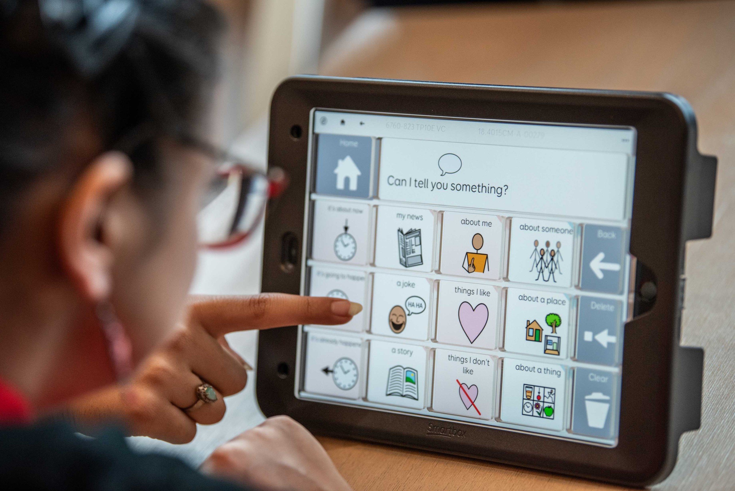 Person using AAC communication device with AI assistance, showing empowerment through technology